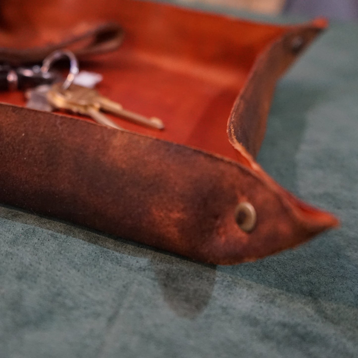 Brown leather tray with keys on a textured surface