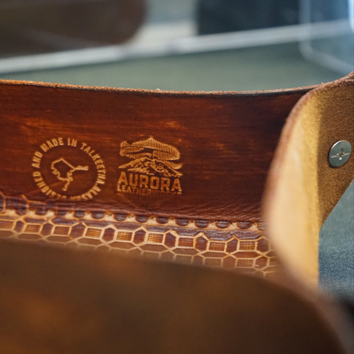 Close-up of a brown leather product with embossed branding on a blurred background