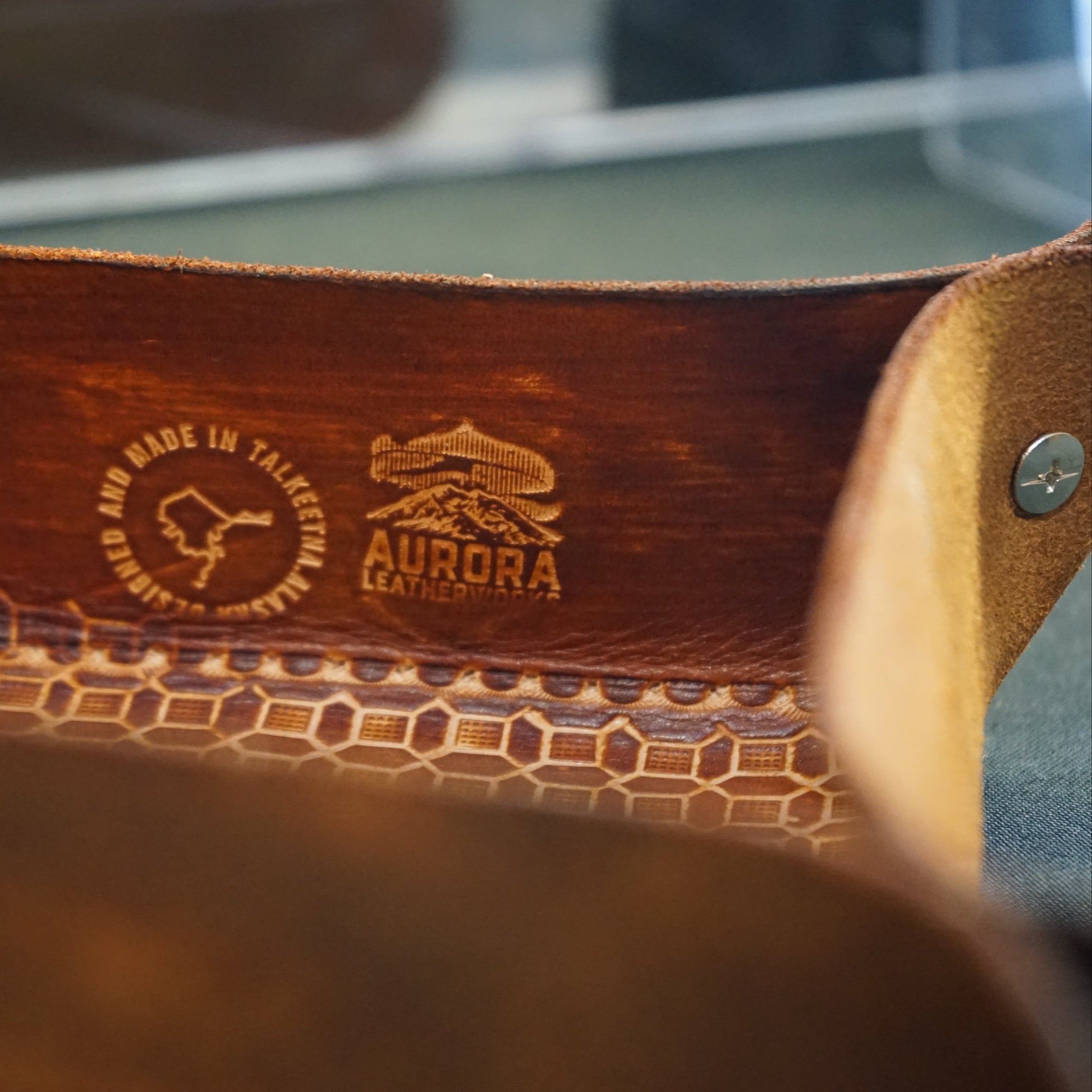 Close-up of a brown leather product with embossed branding on a blurred background