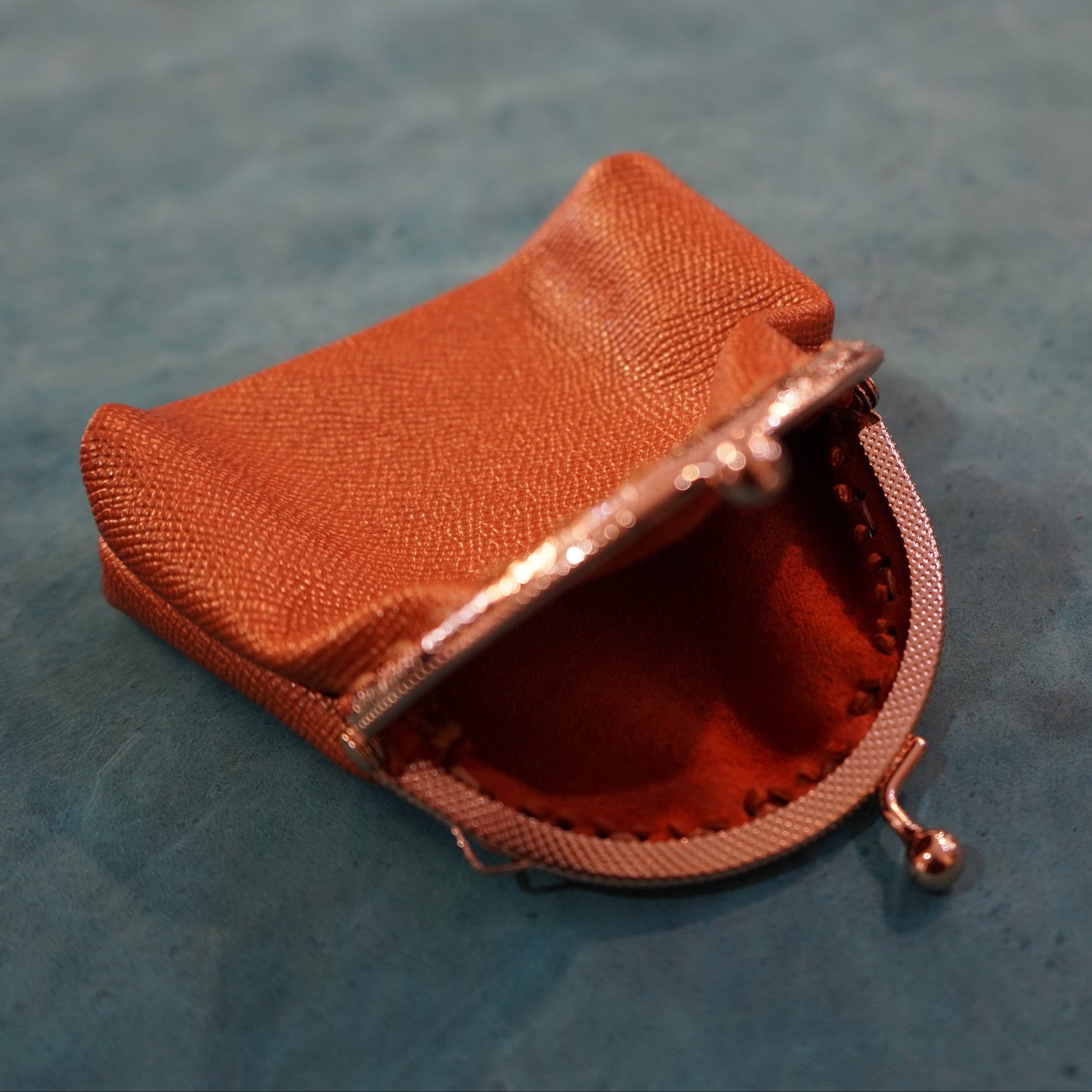 Small brown fabric pouch on a textured blue surface
