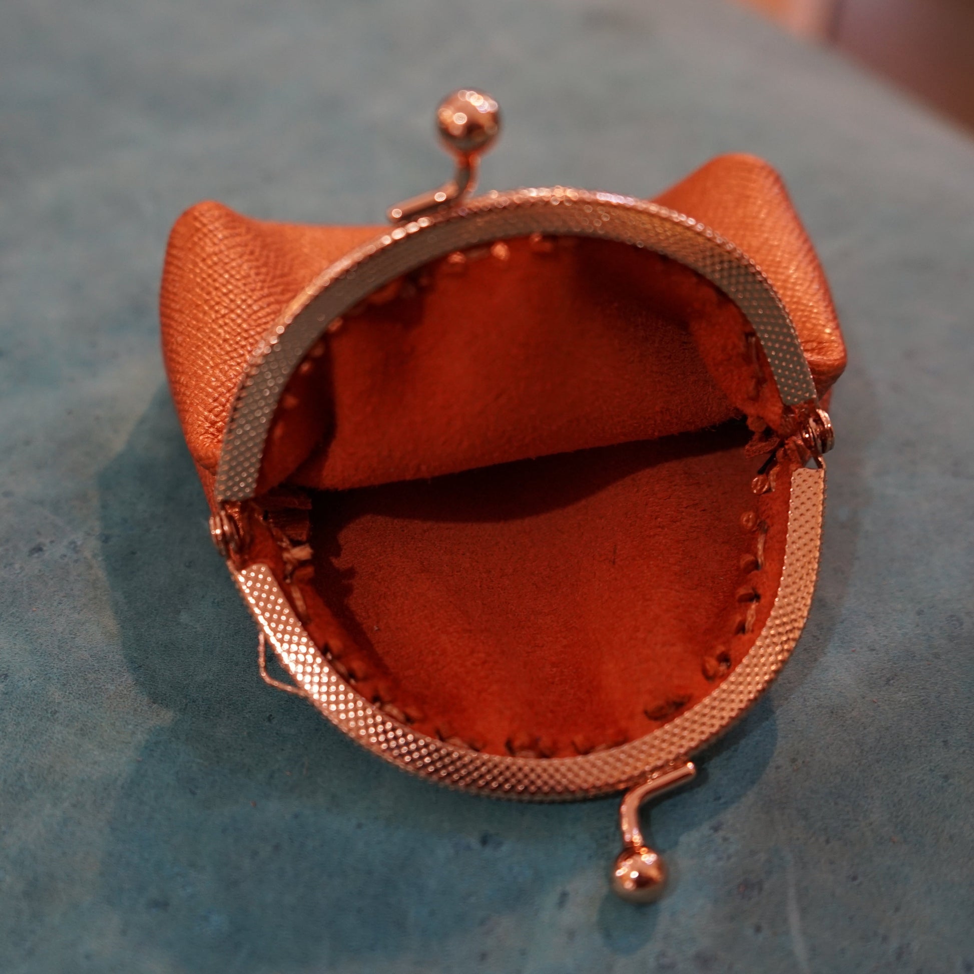 Small orange pouch with a metal clasp on a textured surface