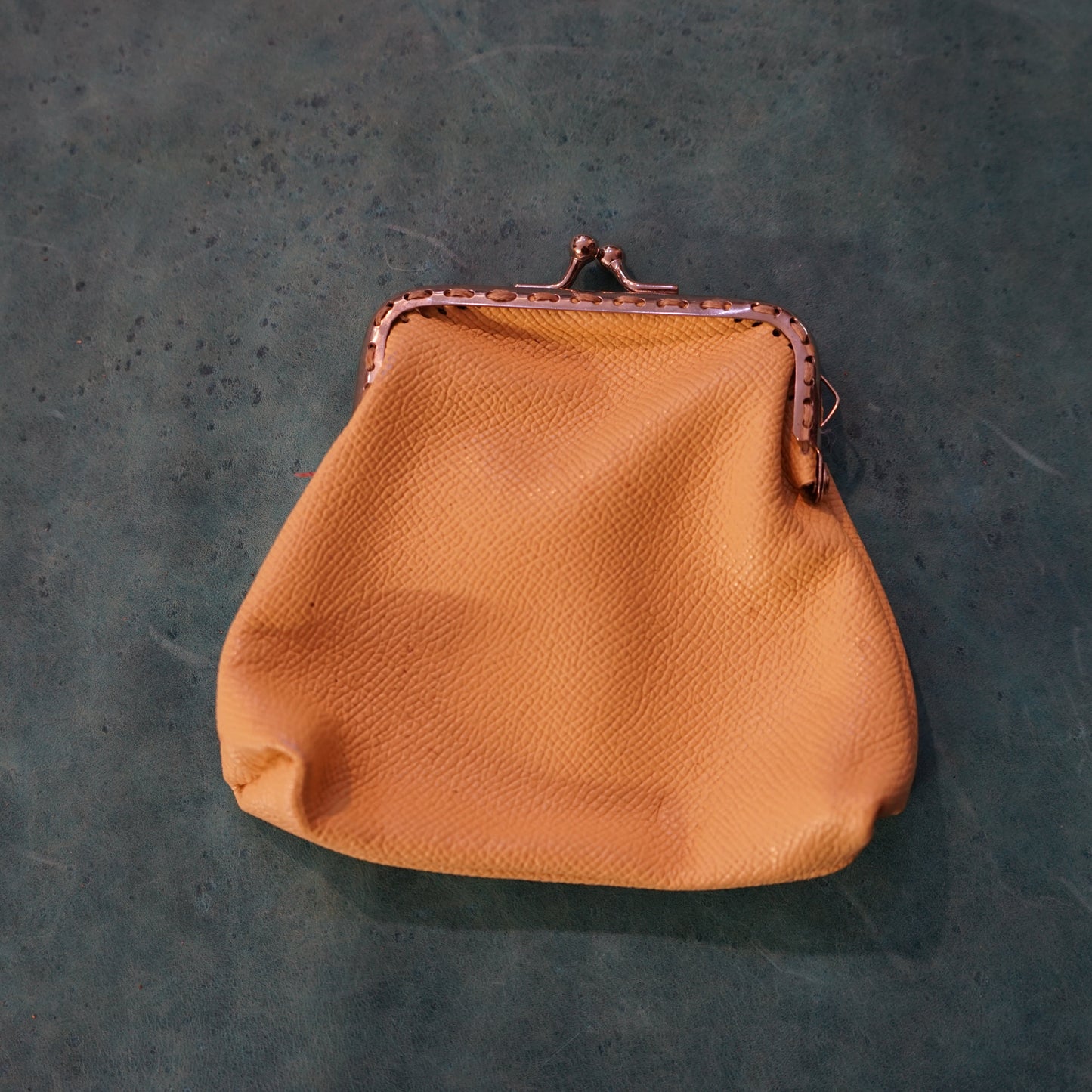 Brown leather purse on a textured green surface