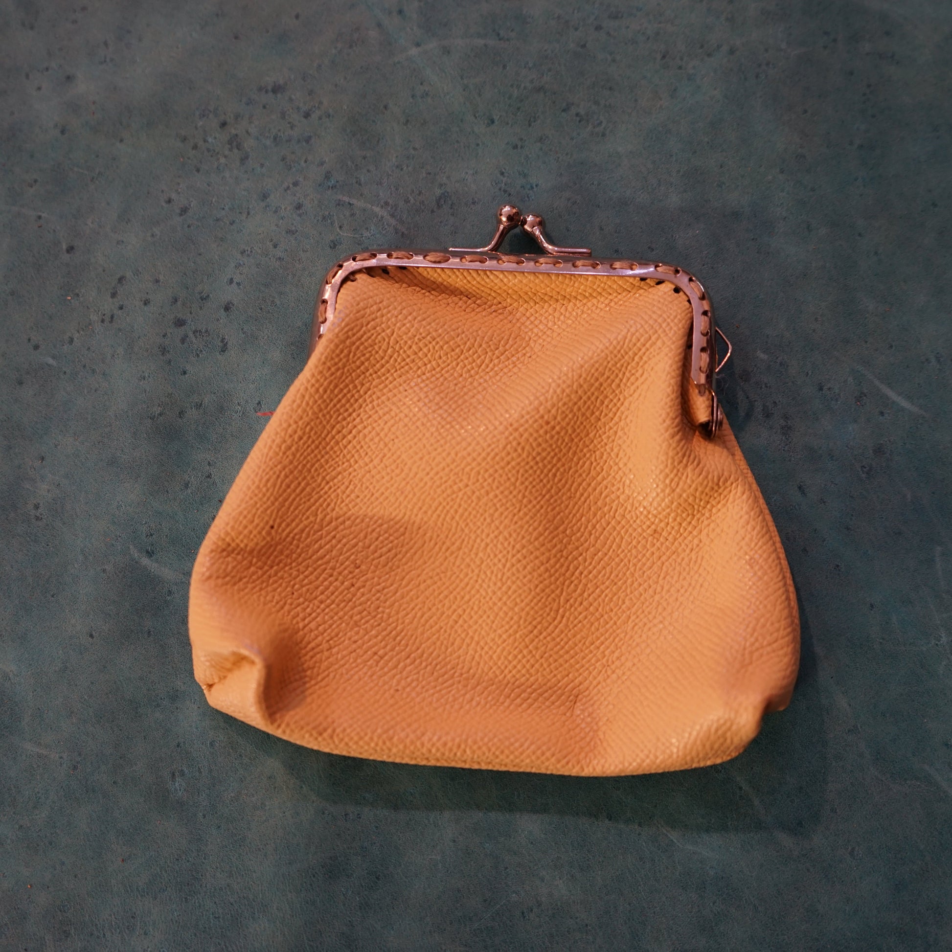 Brown leather purse on a textured green surface